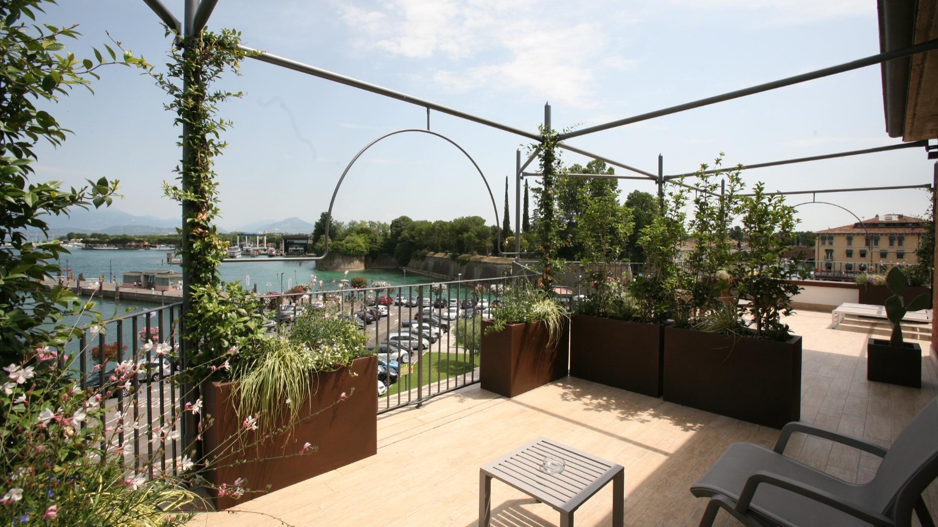 Terrace with lake view, plants, and modern furniture.