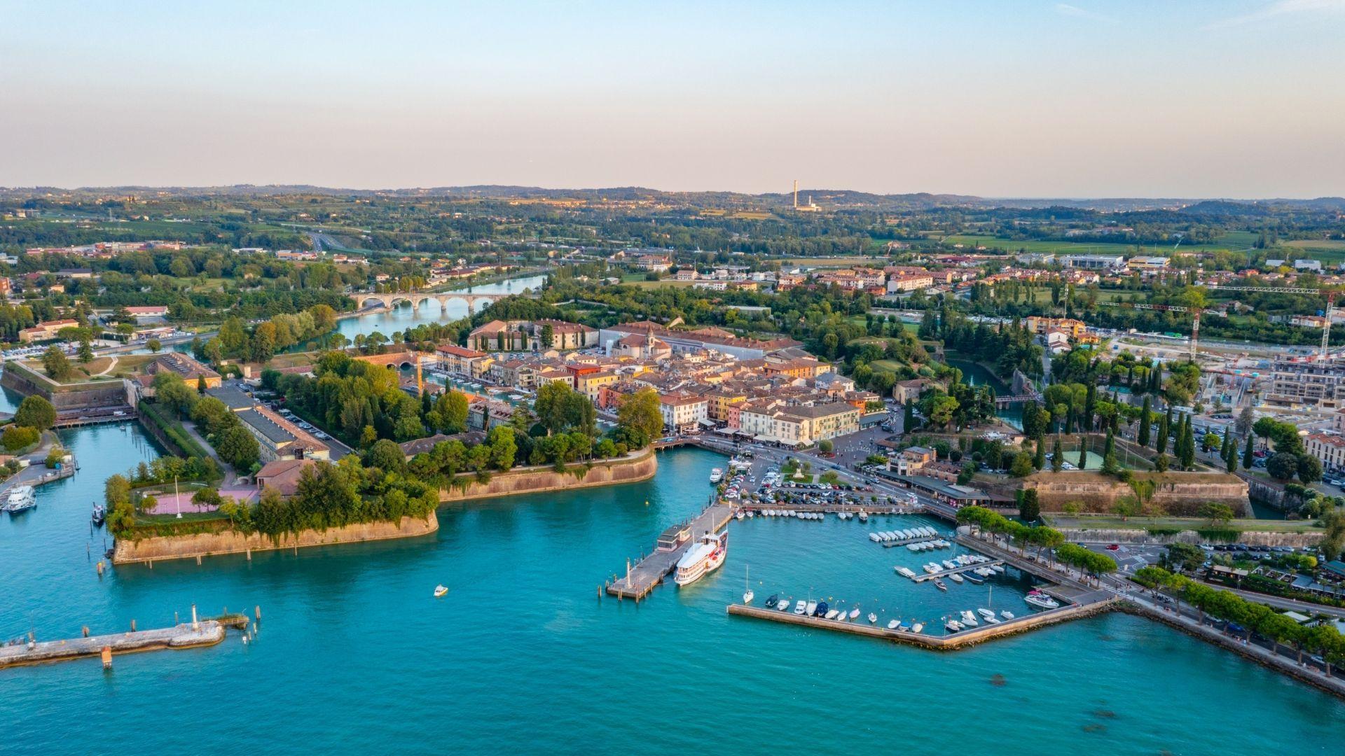 Veduta aerea di una città con porto e paesaggio verde circostante.