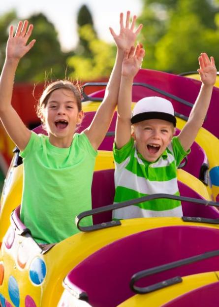 Due bambini felici su una giostra colorata al parco divertimenti.