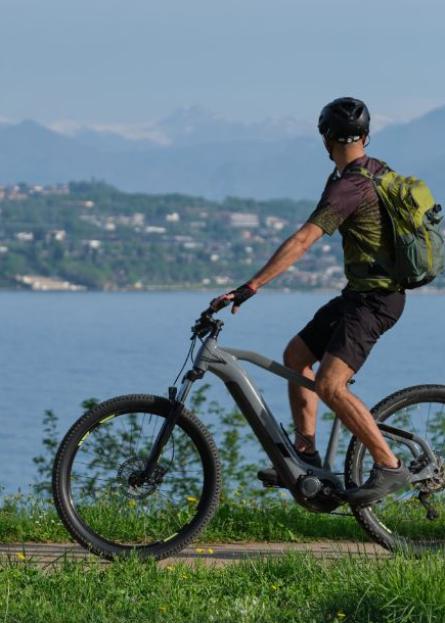 Ciclista su e-bike percorre un sentiero panoramico vicino a un lago.