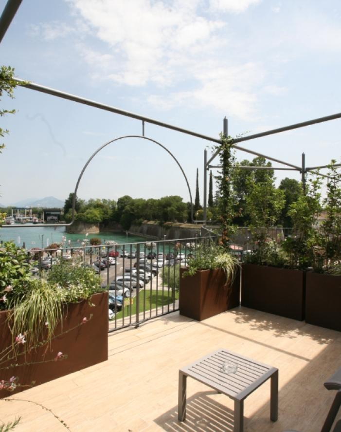 Terrazza con vista sul lago, piante verdi e arredi moderni.