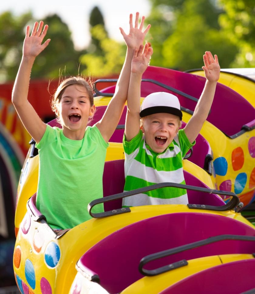 Due bambini sorridenti su una giostra colorata al parco divertimenti.