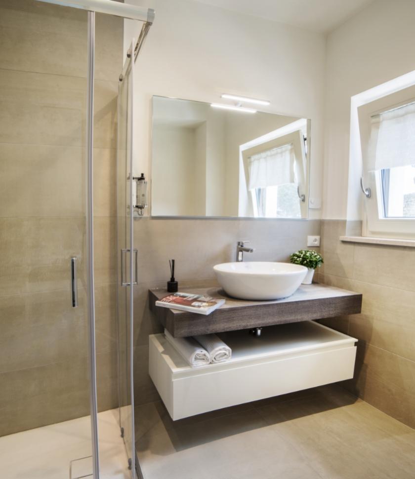 Bagno moderno con doccia, lavabo e specchio.